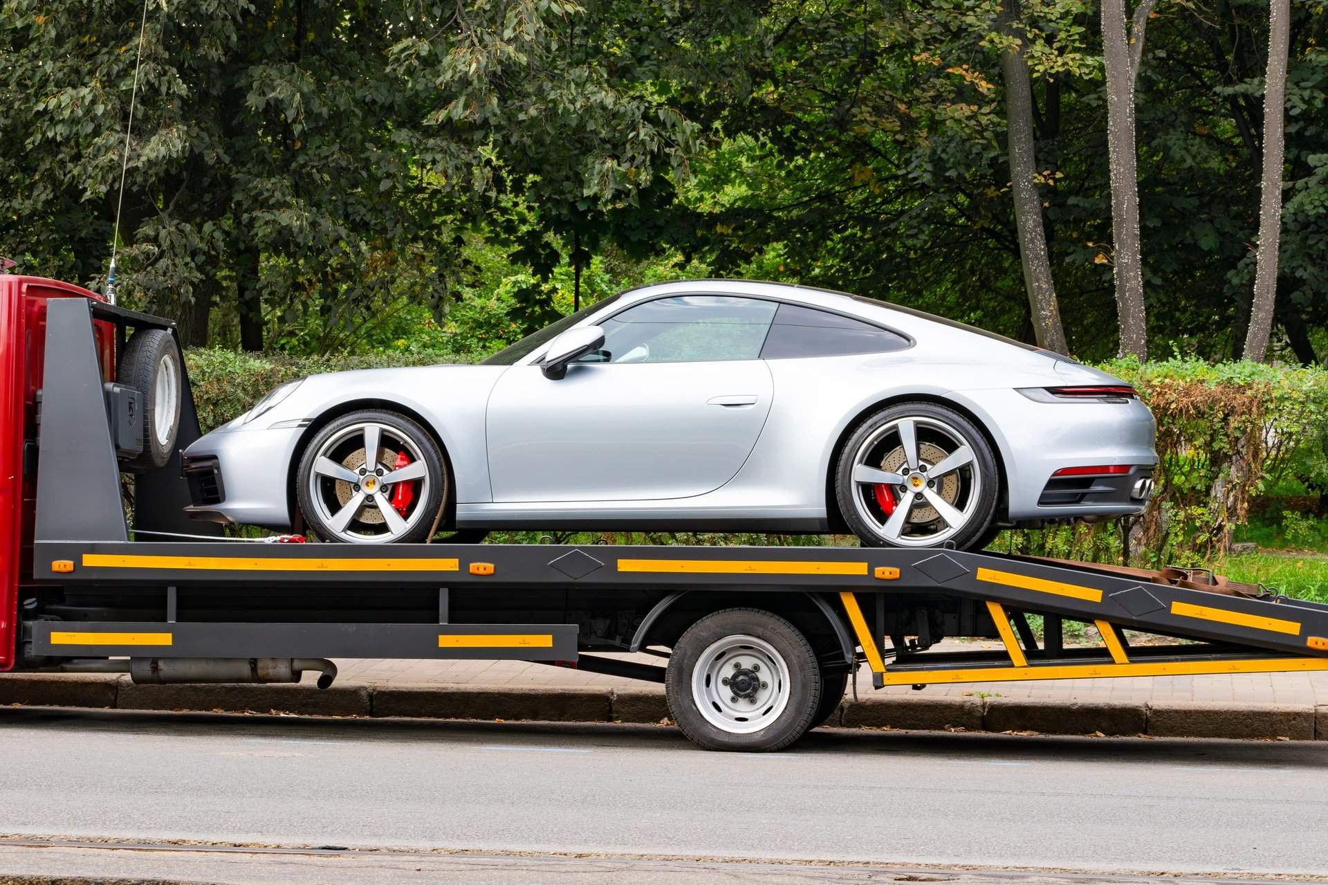 Silver Porsche 911 loaded onto a tow truck for professional enclosed transportation
