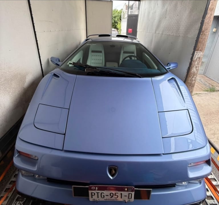 Blue sports car parked in narrow alleyway between concrete walls