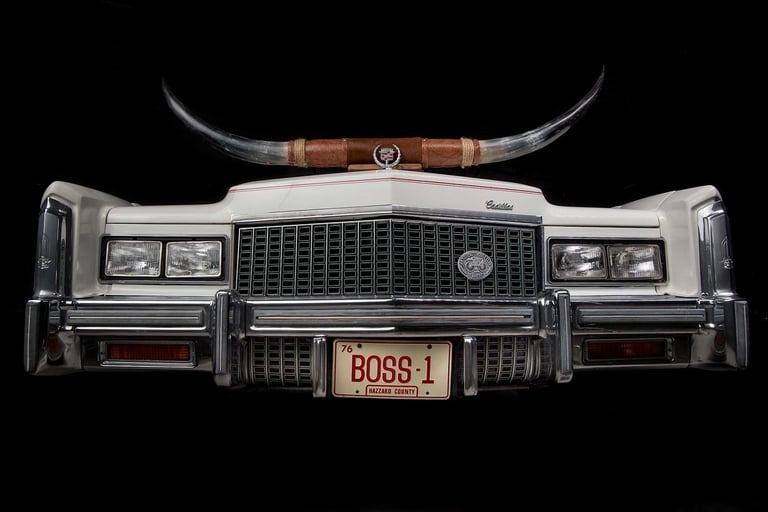 Front view of a classic silver Cadillac with horned hood ornament and BOSS-1 license plate on black background