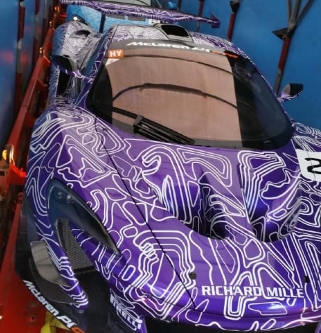 Purple sports car with abstract white pattern wrap parked on red rack against blue sky