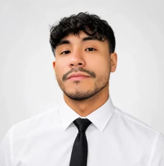 Professional headshot of a man with dark curly hair wearing a white dress shirt and black tie against a white background